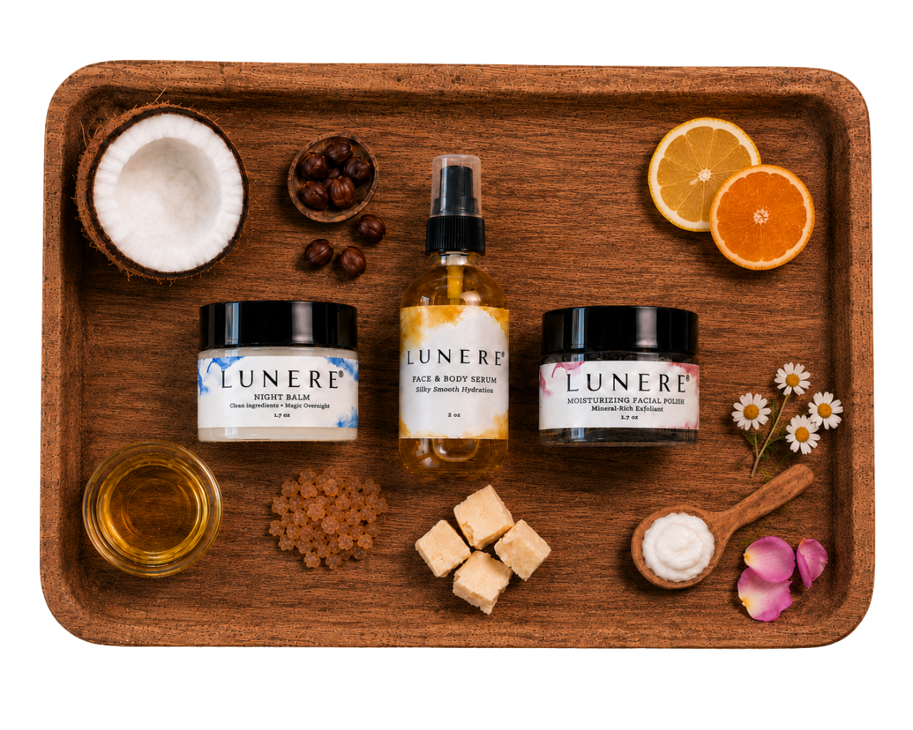 Three Lunere skincare products arranged on a wooden tray with natural ingredients around them: a coconut, orange slices, dried berries, honey, brown sugar, white sugar cubes, chamomile flowers, and pink petals.